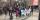 A group of people gathered on a street corner, holding a large banner commemorating the Tutsi genocide in Rwanda.